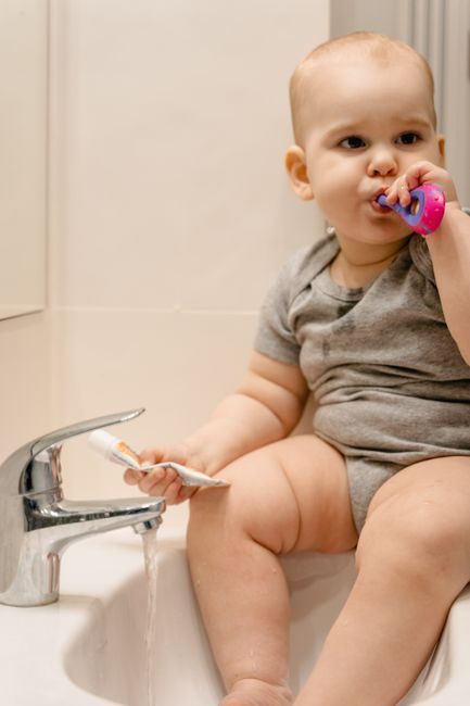 Toddler smiling while brushing their teeth