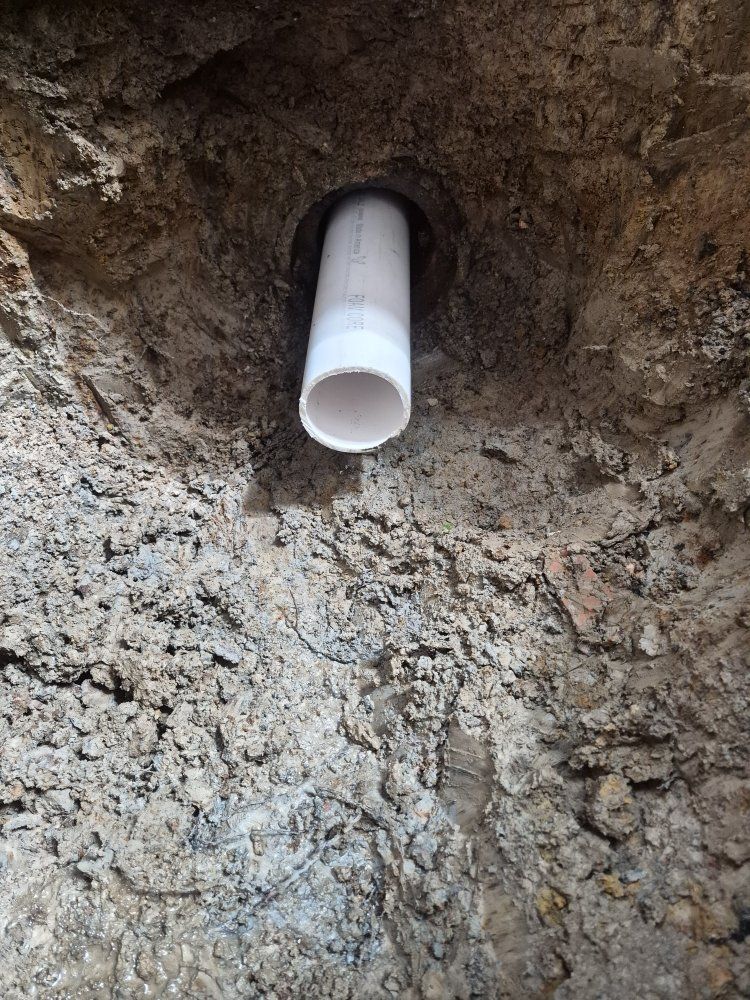 White PVC pipe protruding from a rough dirt wall opening