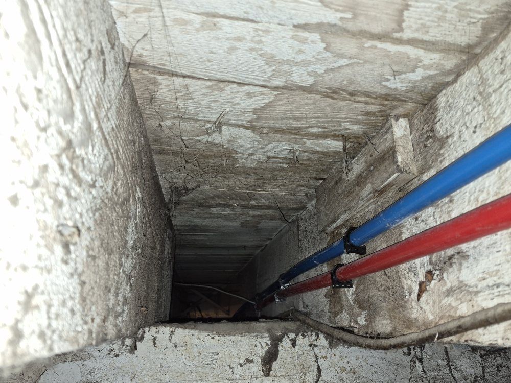 Narrow concrete shaft with blue and red pipes running along the right wall