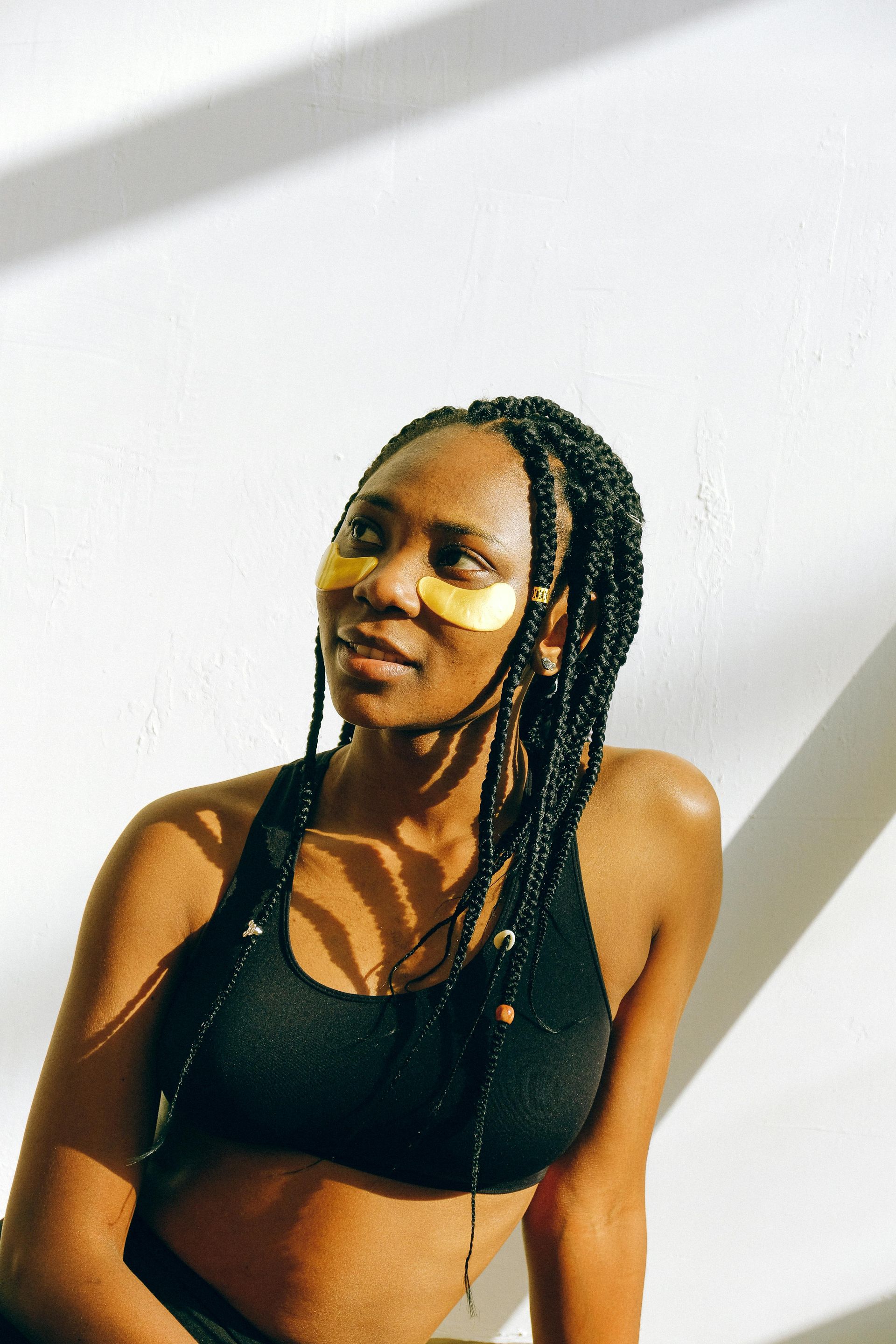 A woman wearing a black braided top and gold eye patches.