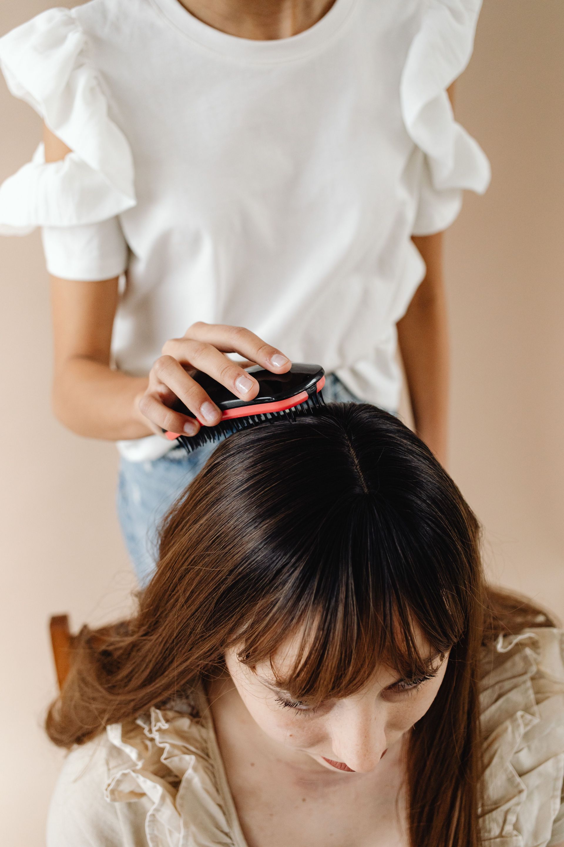 Person gently combing another person's hair in a salon setting
