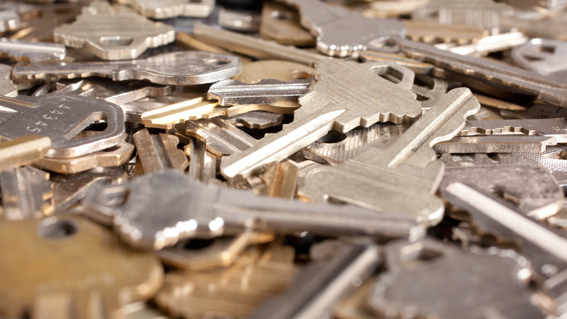 A pile of assorted metal keys scattered on a surface.