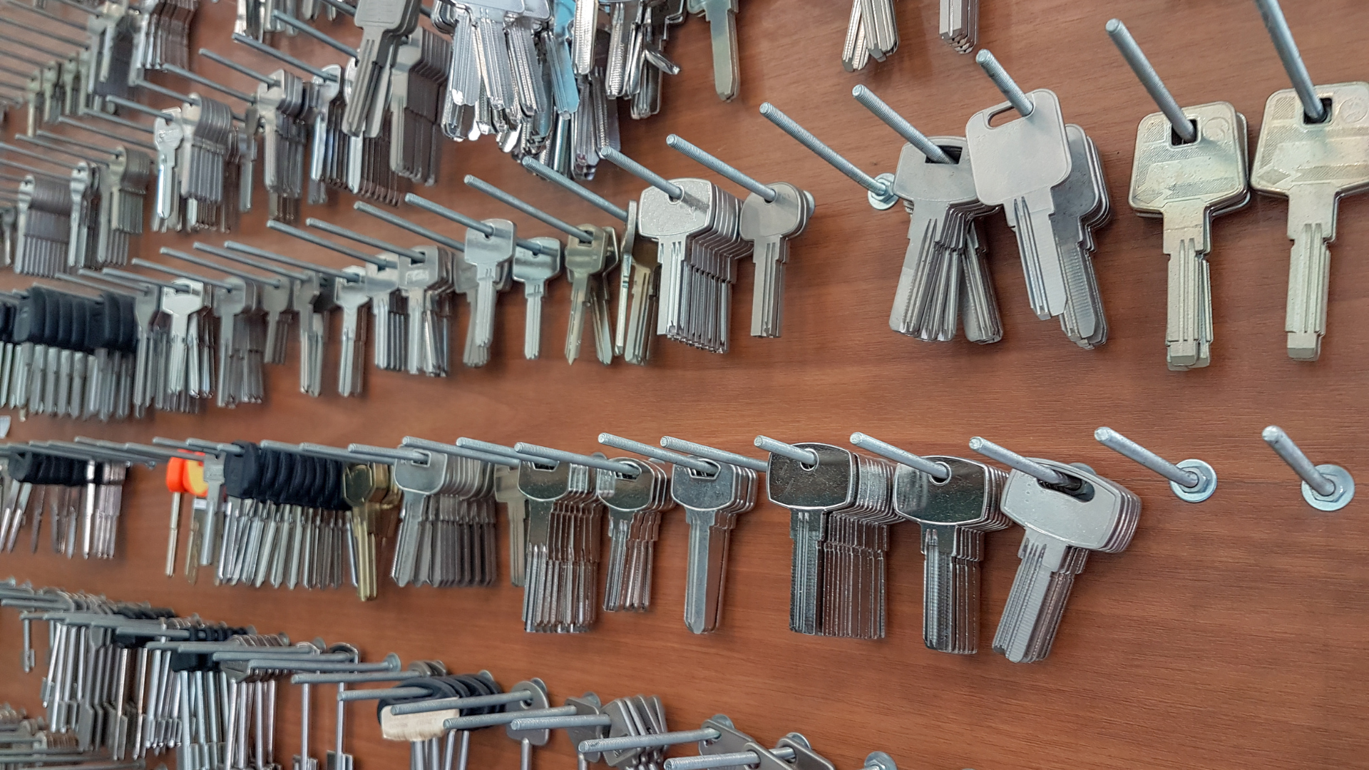 Rows of assorted keys hanging on a wooden wall display