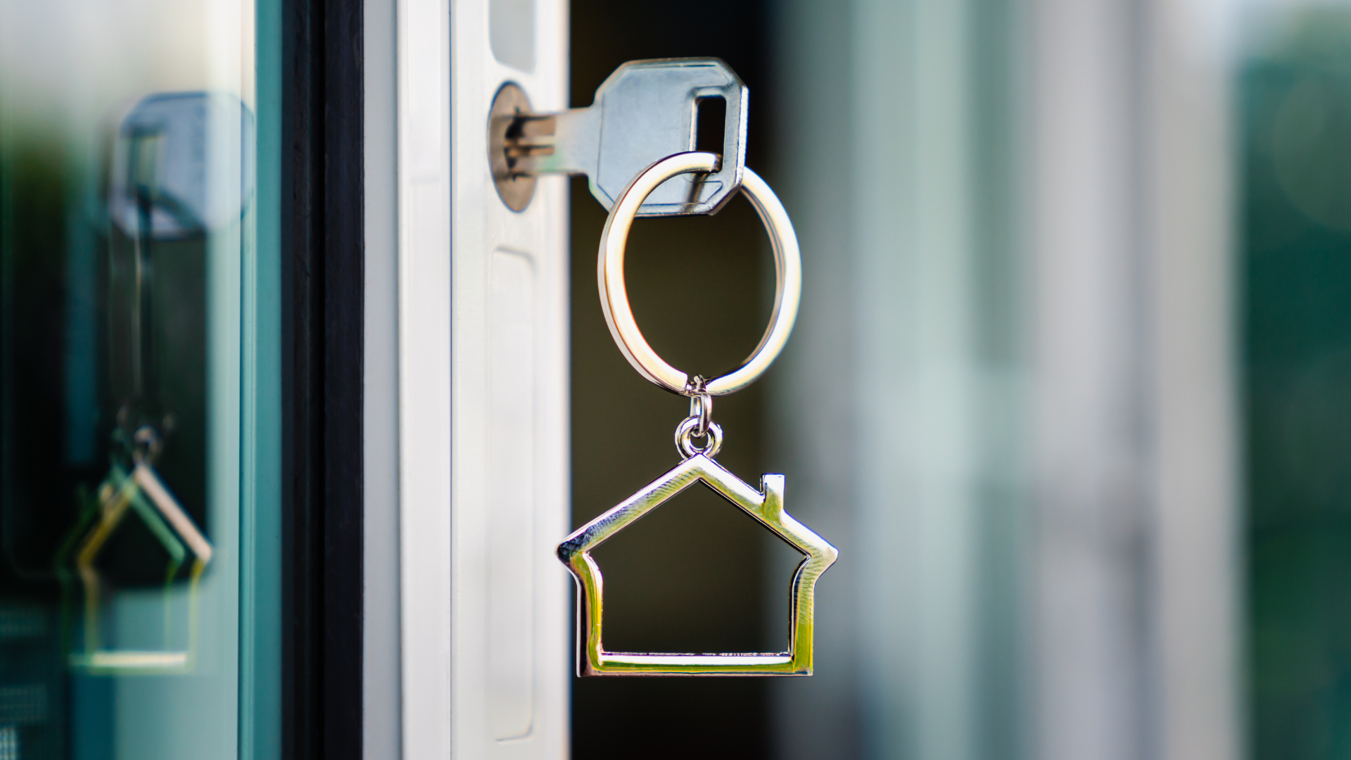Key fob shaped like a house hanging from a door lock on a glass door