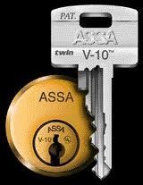 Silver ASSA V-10 key above gold ASSA V-10 lock cylinder on black background