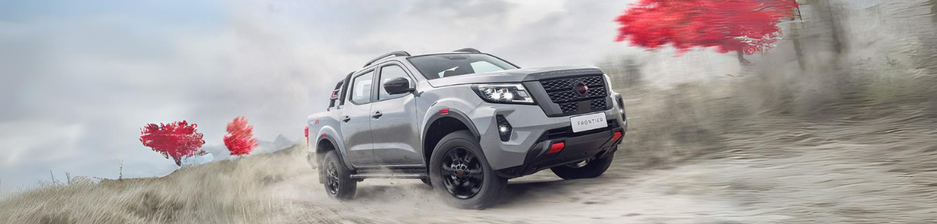 Uma caminhonete Nissan está dirigindo por uma estrada de terra.