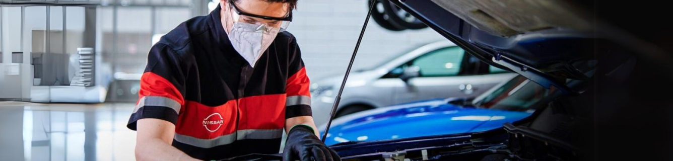 Um homem está trabalhando em um carro com o capô aberto.
