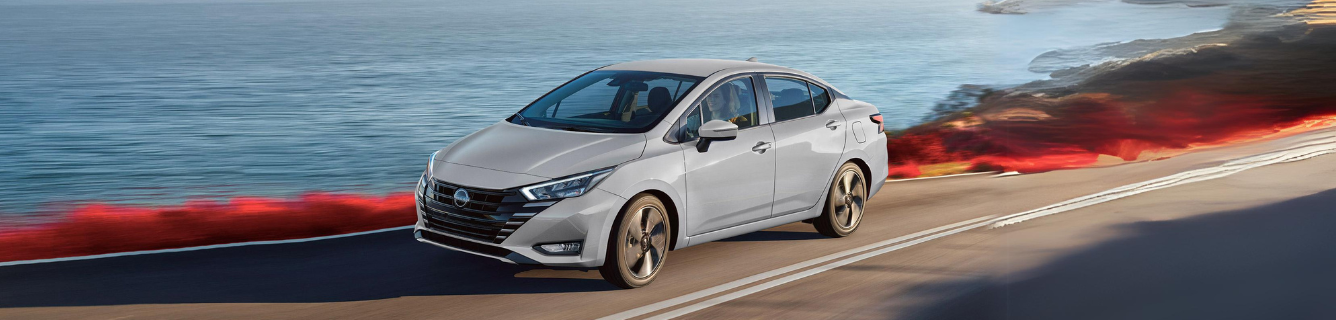 Um carro branco está dirigindo por uma estrada próxima ao oceano.