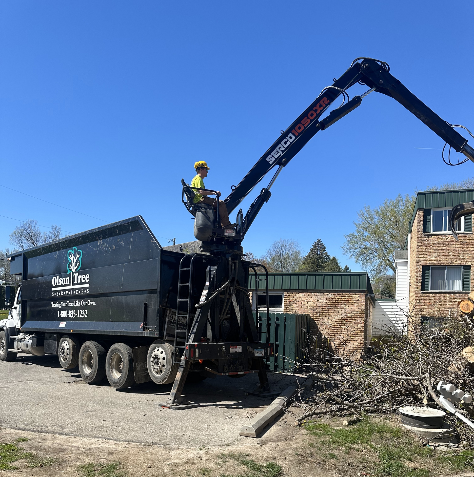 A man is standing on top of a truck with a crane attached to it