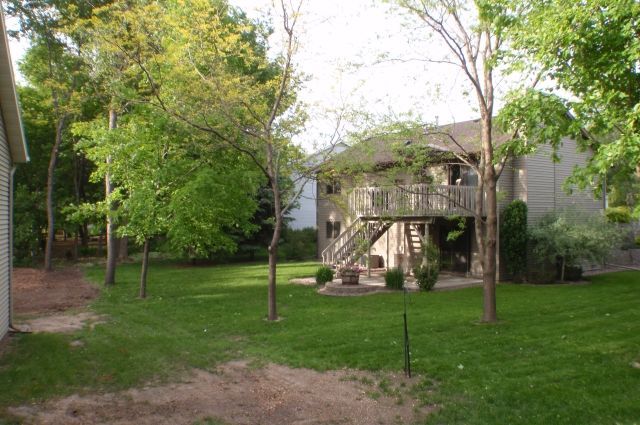 A house with a large lawn and trees in front of it