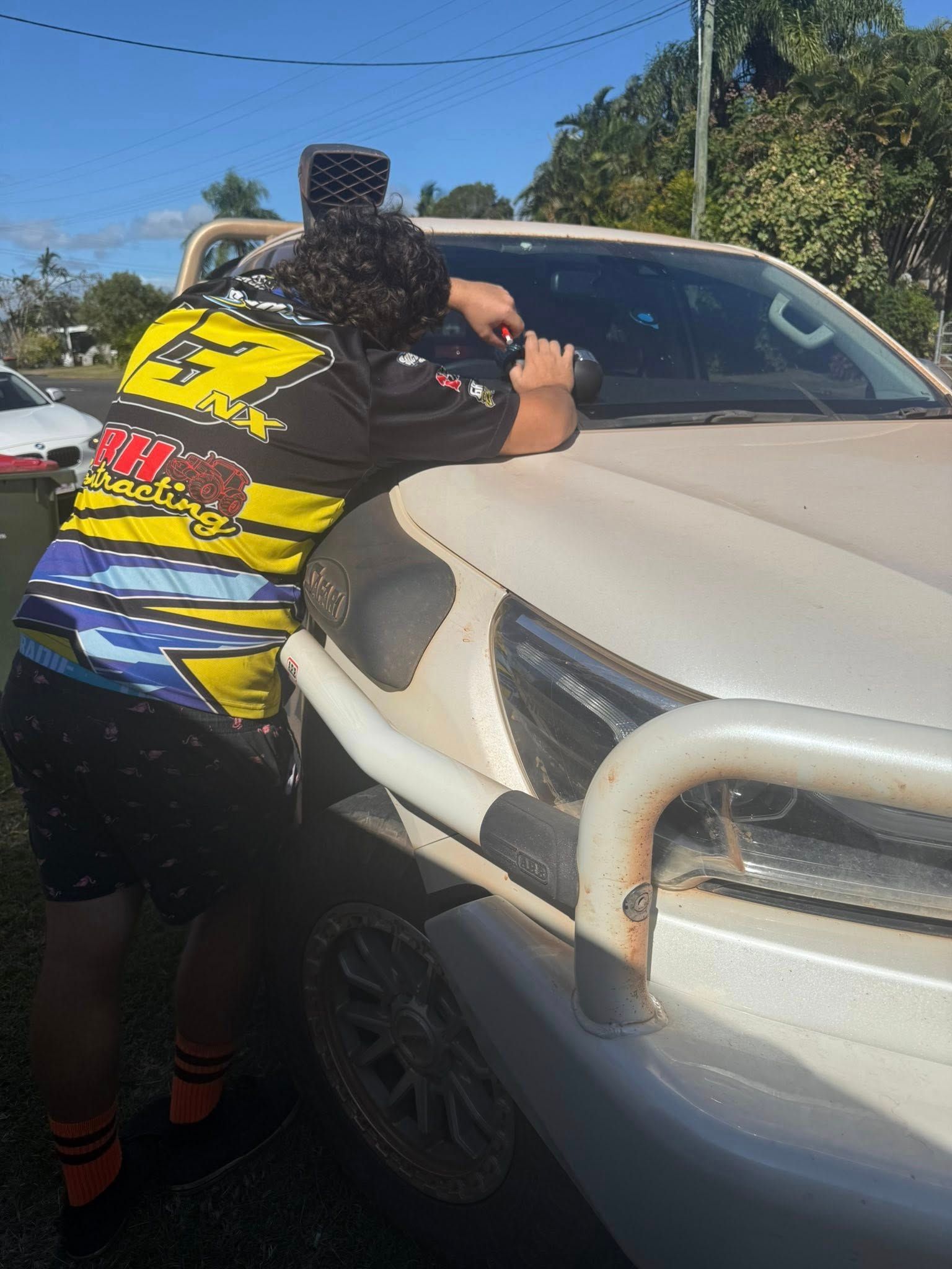 A Person Wearing a Yellow and Black Jersey Reaches — Far North Windscreens in Mareeba, QLD