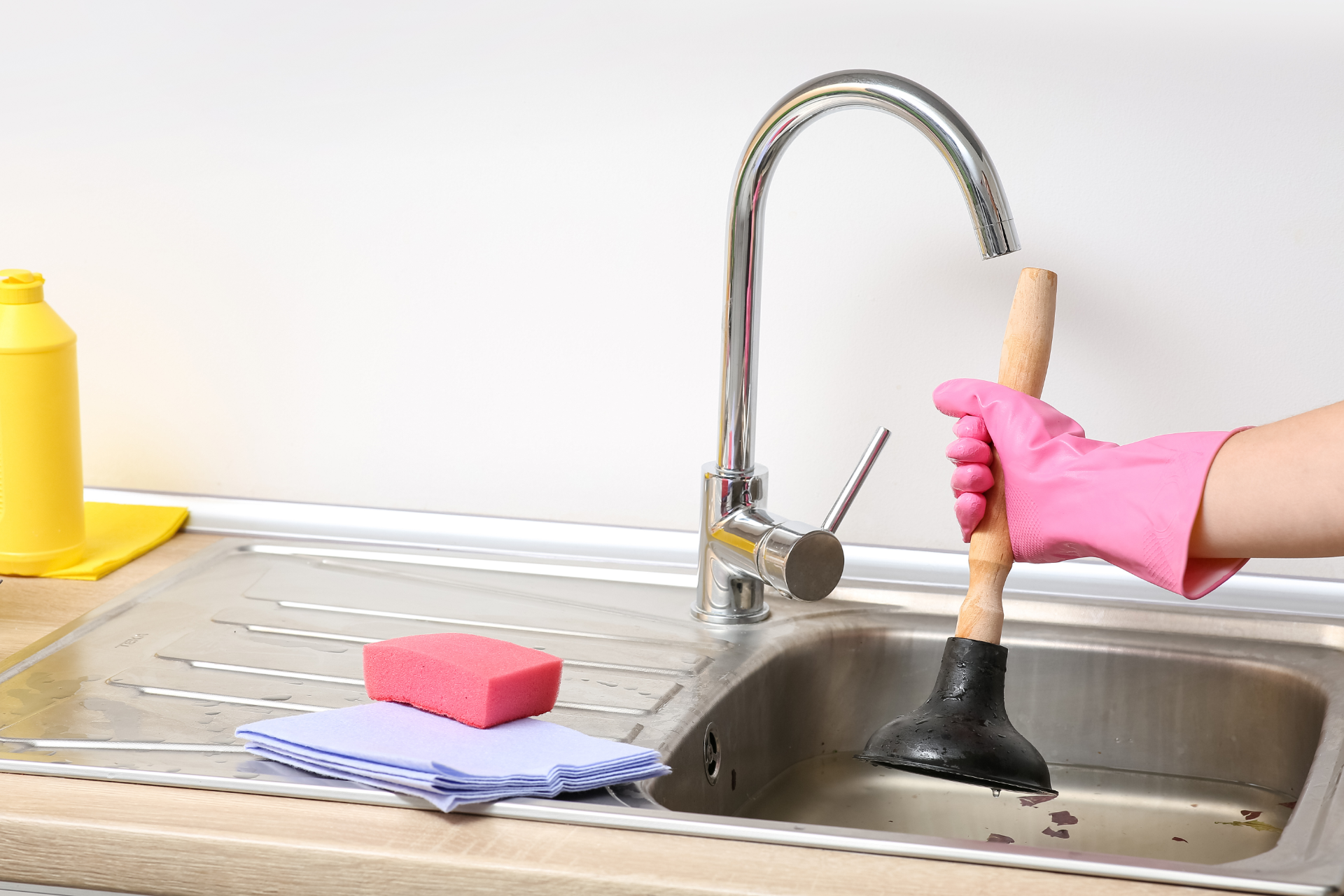 Woman brushing a toddler's teeth in a bathroom; child sits on counter, orange sweater.