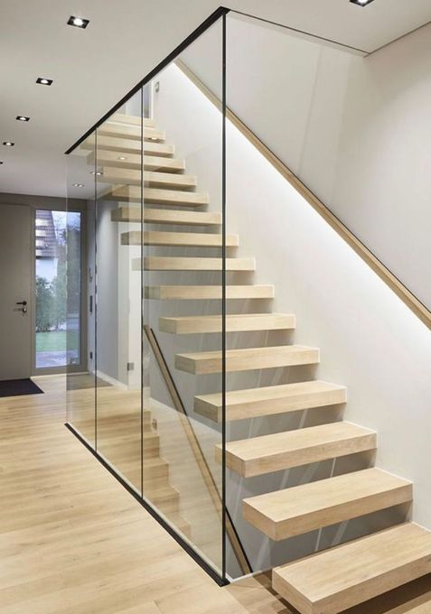 Escalier flottant en bois avec panneaux de verre et rampe en bois dans une maison moderne.