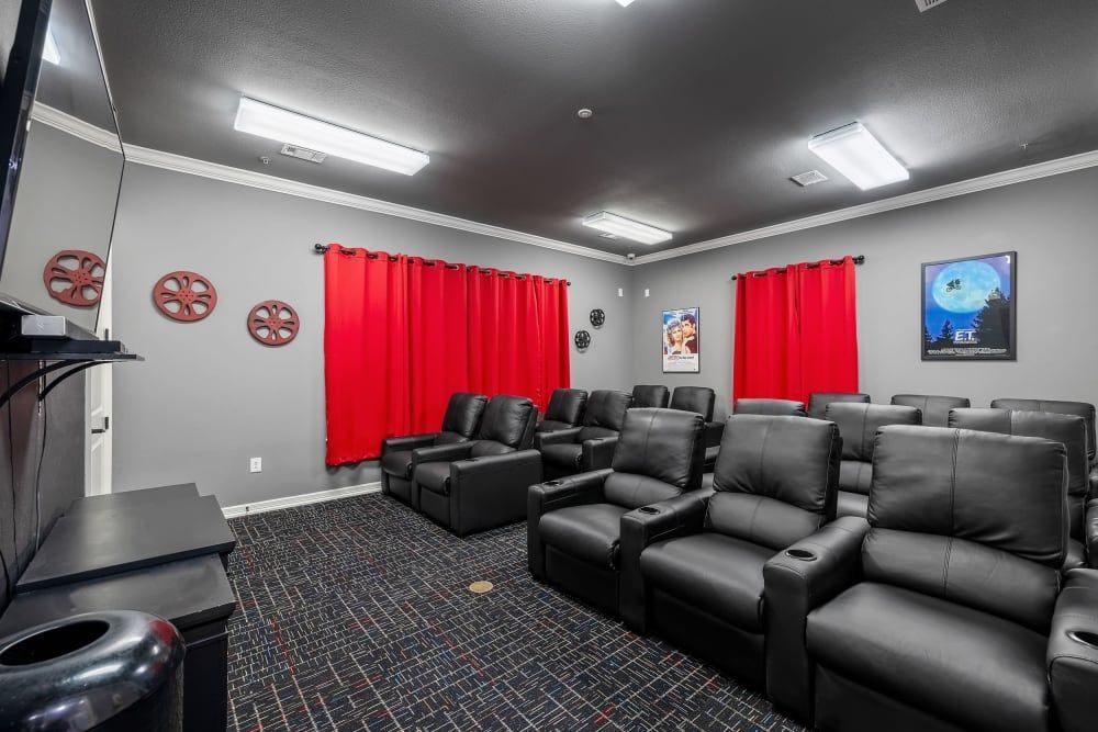 Theater with black leather chairs and red curtains at Marquis Rockwall in Rockwall, TX.