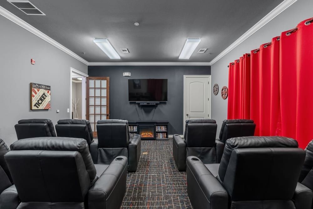 Community movie theater with black chairs and a flat-screen tv at Marquis Rockwall in Rockwall, TX.