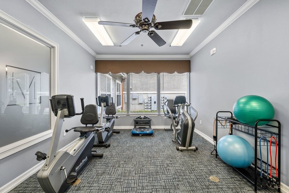 A fitness center with a lot of exercise equipment and a ceiling fan at Marquis Rockwall in Rockwall, TX.