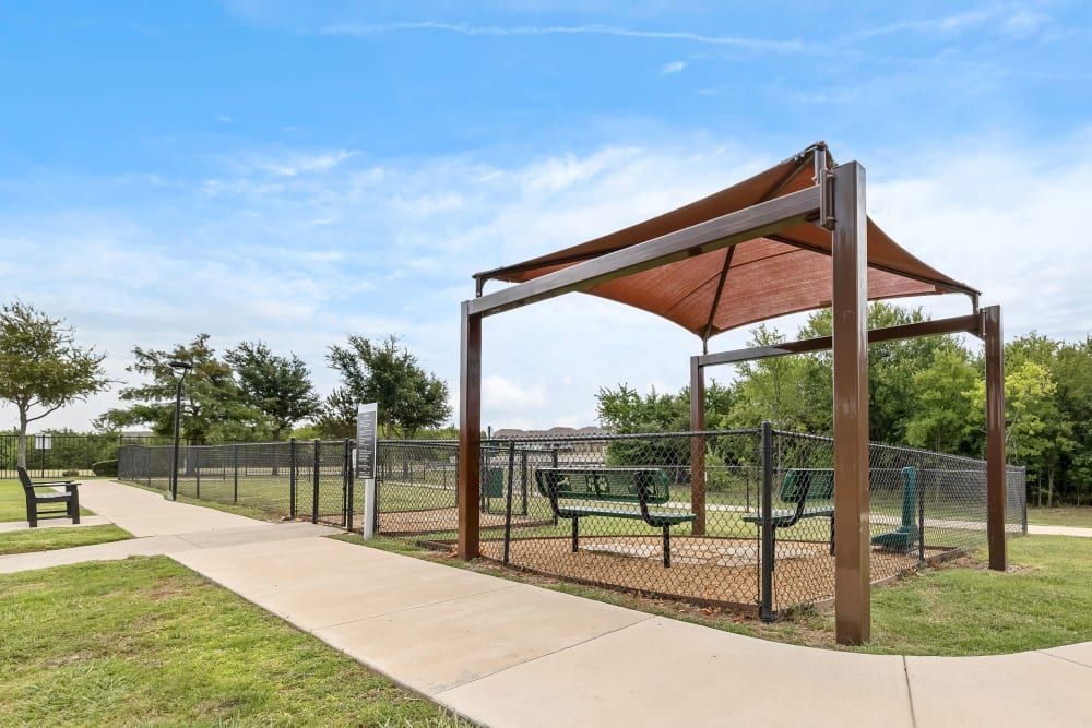 There is a picnic table under a canopy in the park at Marquis Rockwall in Rockwall, TX.