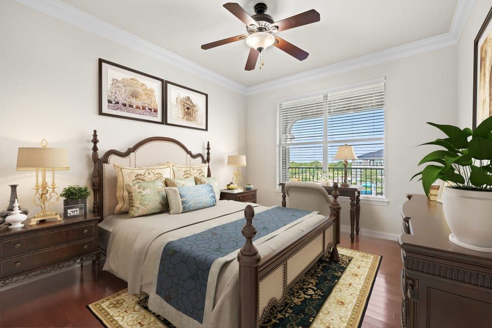 Senior living bedroom with a large bed, a ceiling fan, and a large window at Marquis Rockwall in Rockwall, TX.