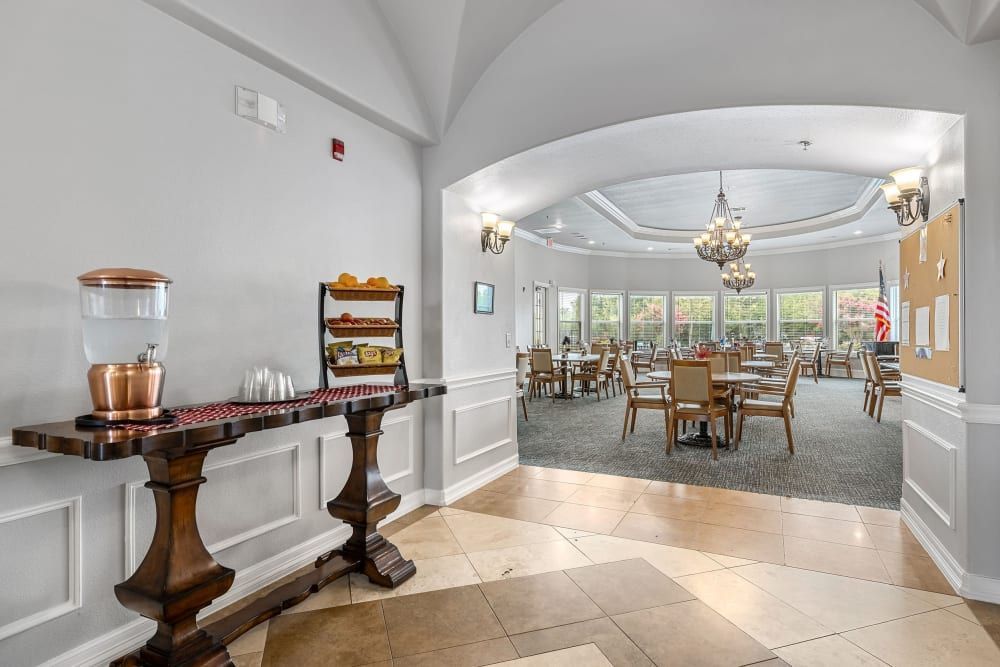 A large dining room with tables and chairs and a table with a water dispenser on it at Marquis Rockwall in Rockwall, TX.