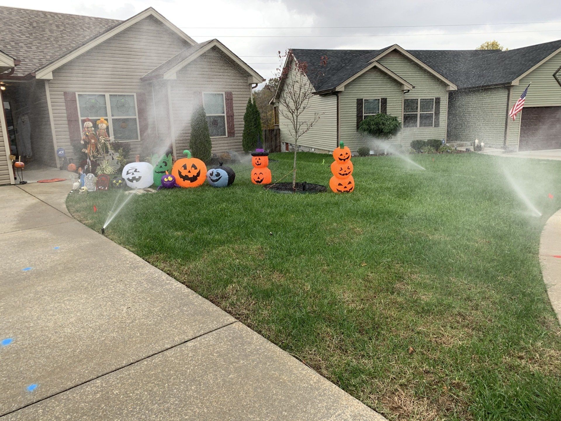 Halloween decorations on a front lawn, including pumpkins, a skeleton, and orange ghosts by a house