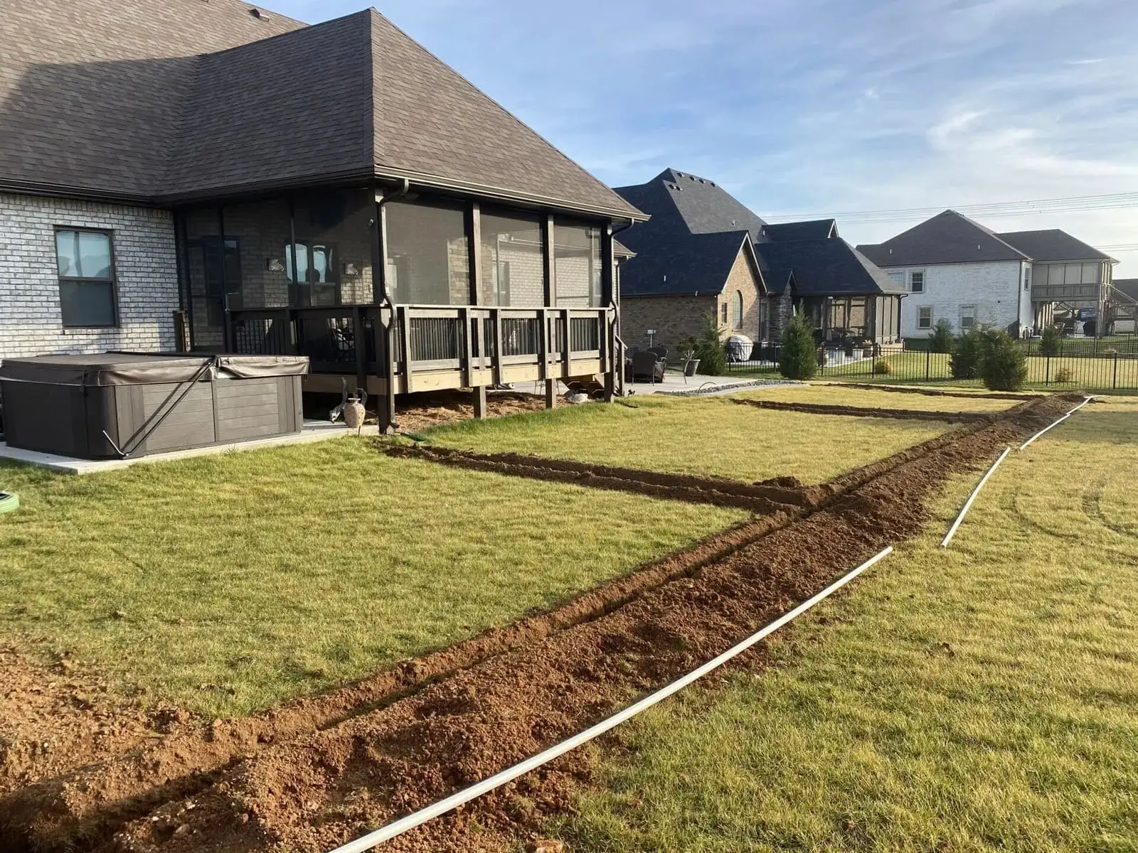 Backyard with fresh mulch pathways, a lawn, and suburban houses in the background