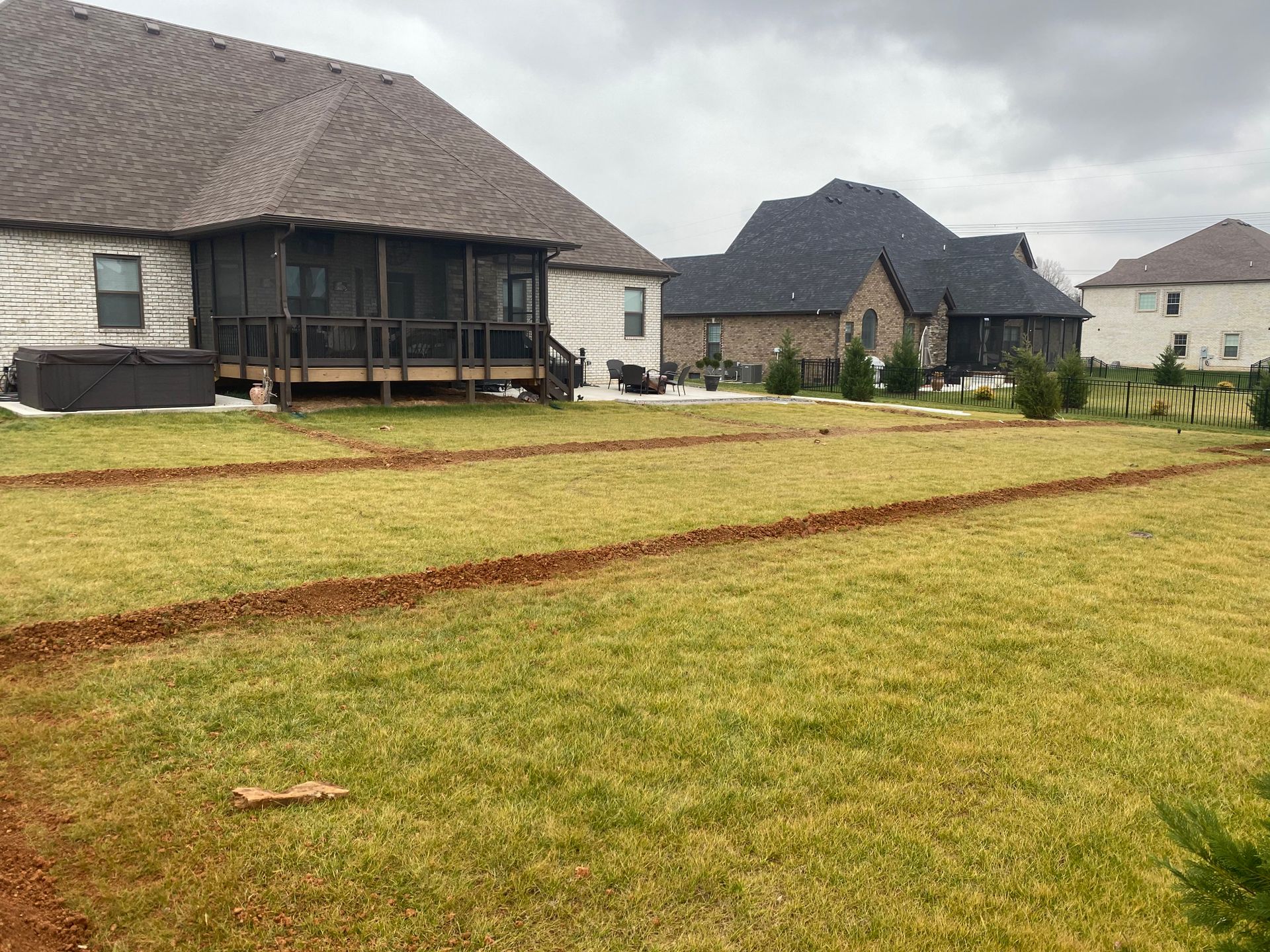 Suburban houses behind a grassy yard with a muddy track in the foreground