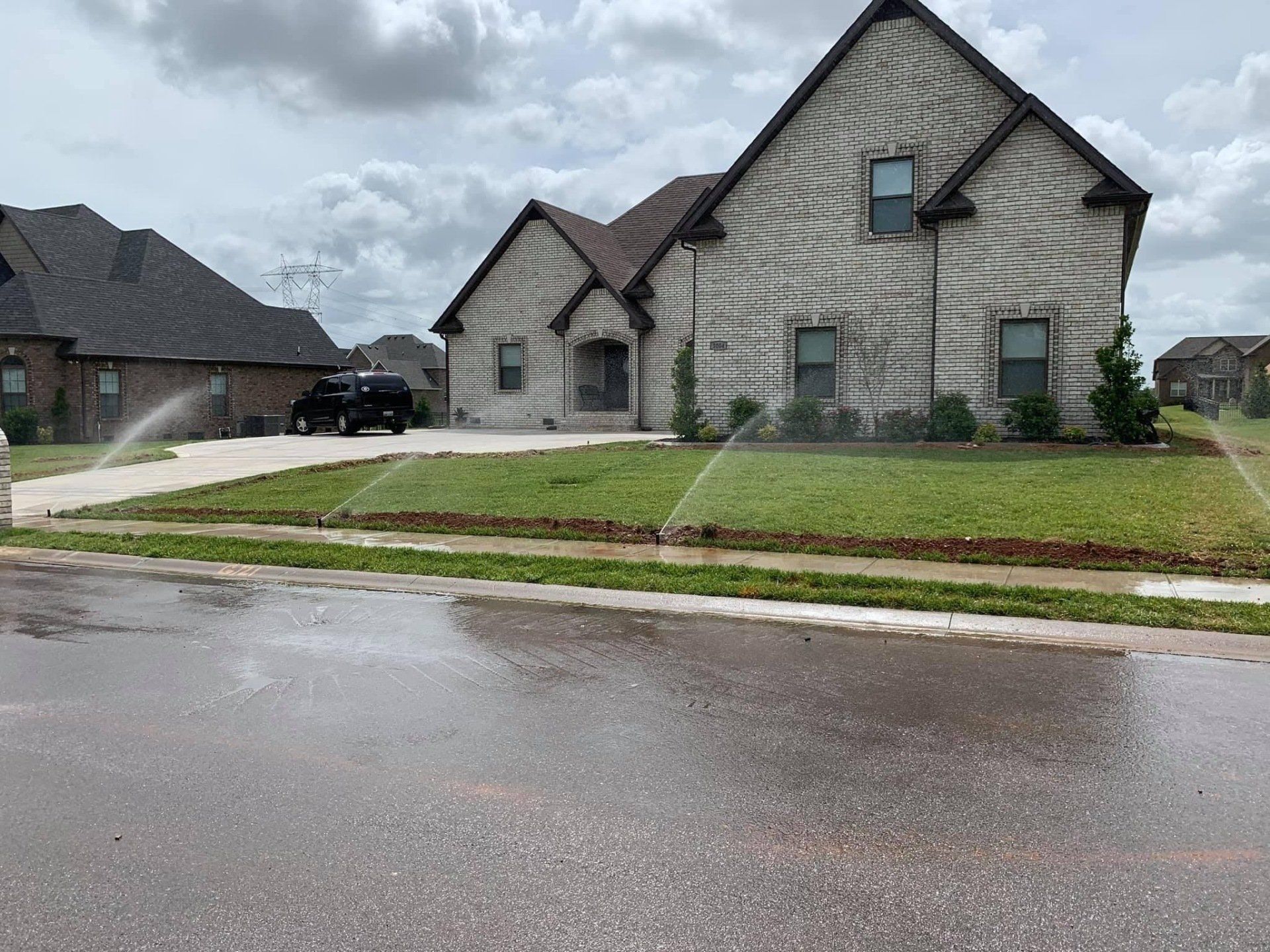 Suburban house with stone siding and wet driveway on a rainy street