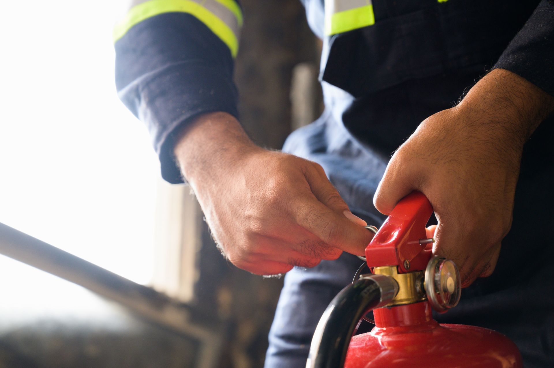 Worker handling a fire extinguisher valve in protective workwear.