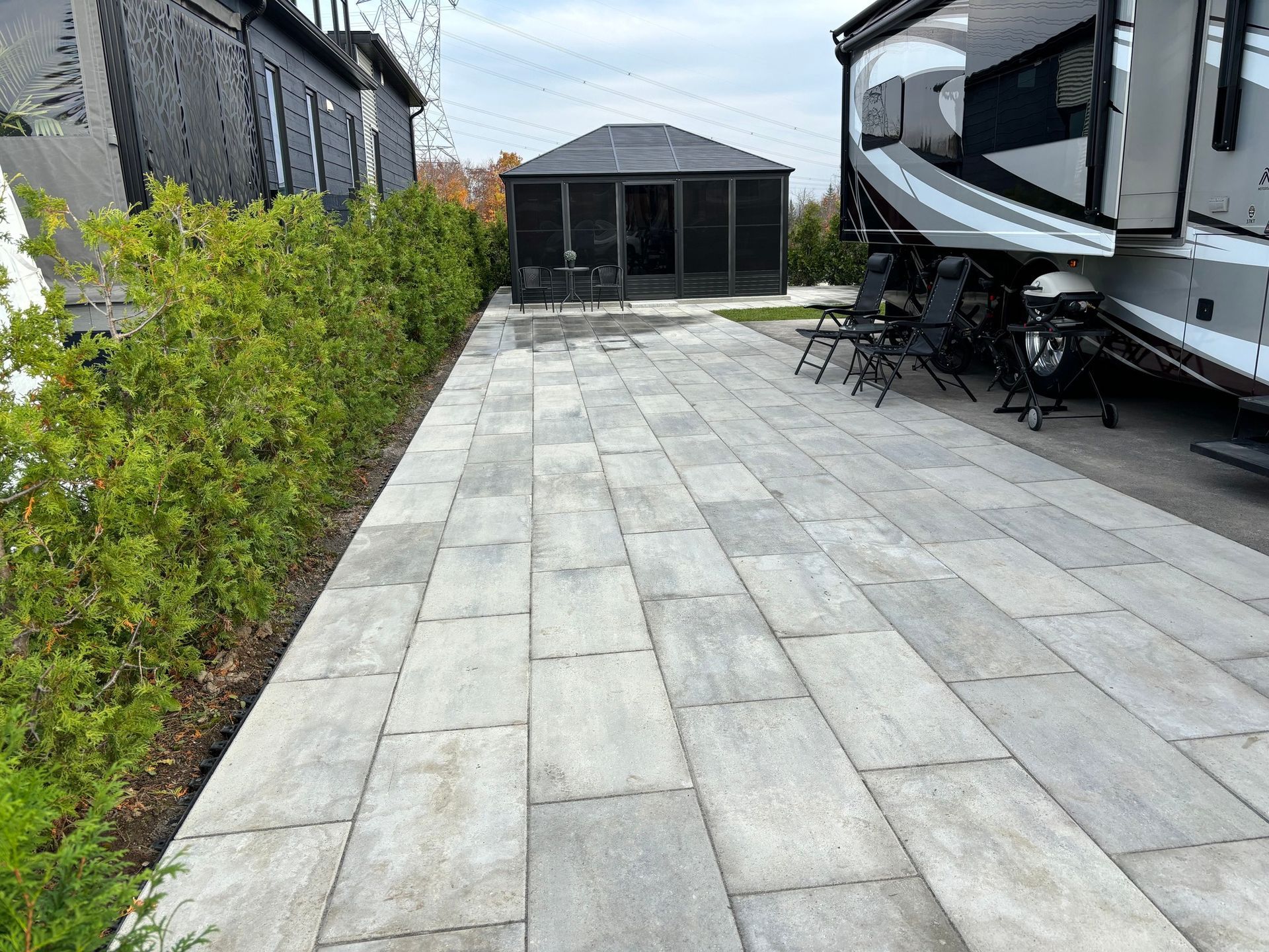 Un patio avec un camping-car garé devant une maison.