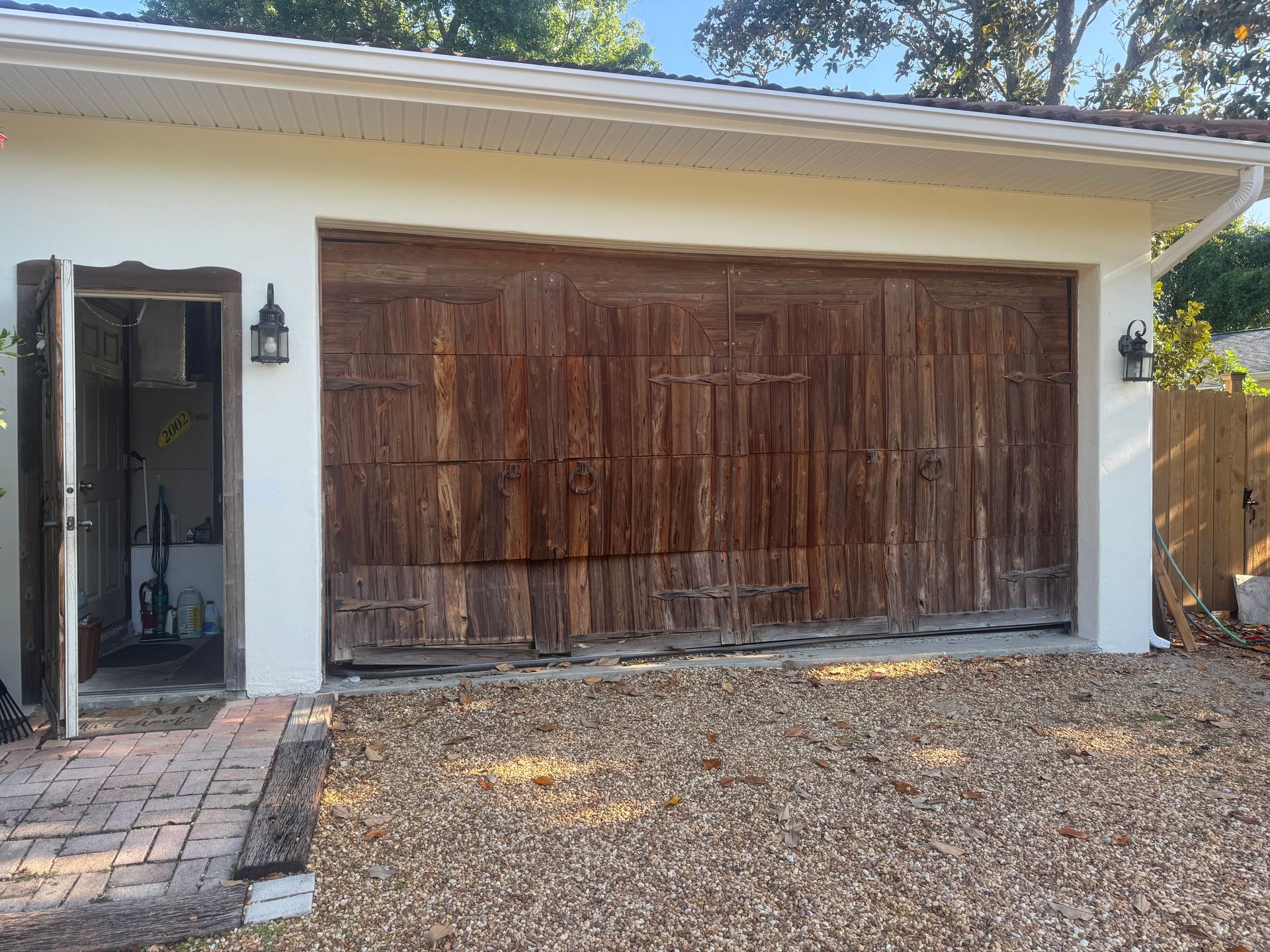 White house exterior with a large weathered wood garage door and a brick walkway beside it