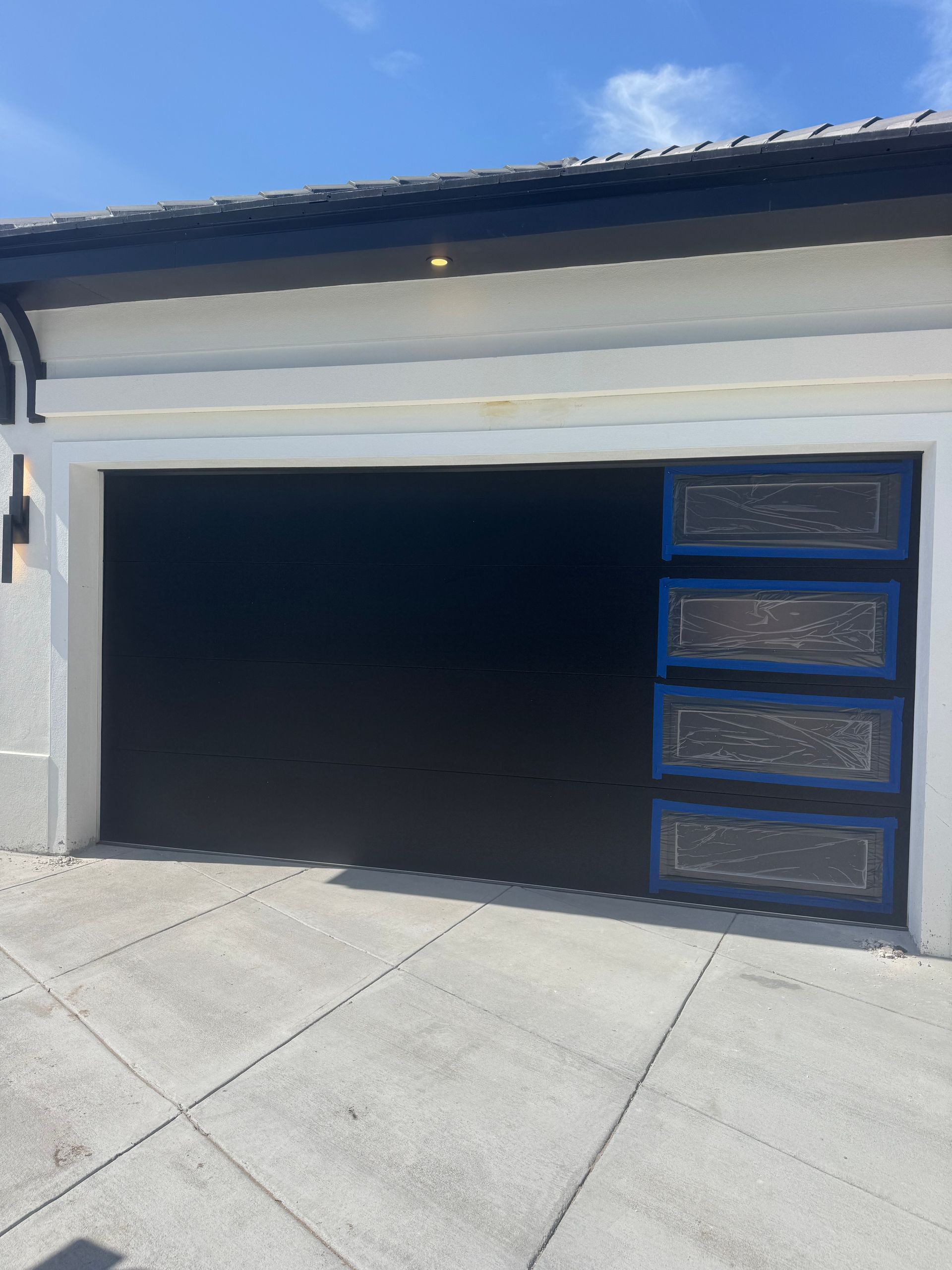 Modern garage with black door panels and white exterior facade in a driveway