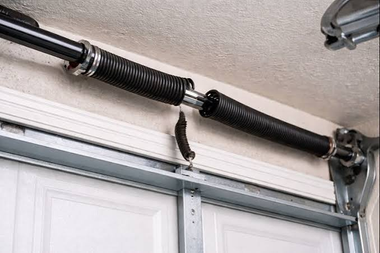 Garage door torsion springs and center cable above a white door.