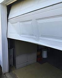 Partially open white garage door revealing a dark garage interior and floor