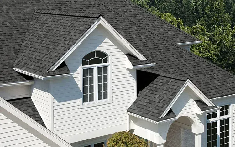 White house with gray shingled roof, dormer window, and white siding.