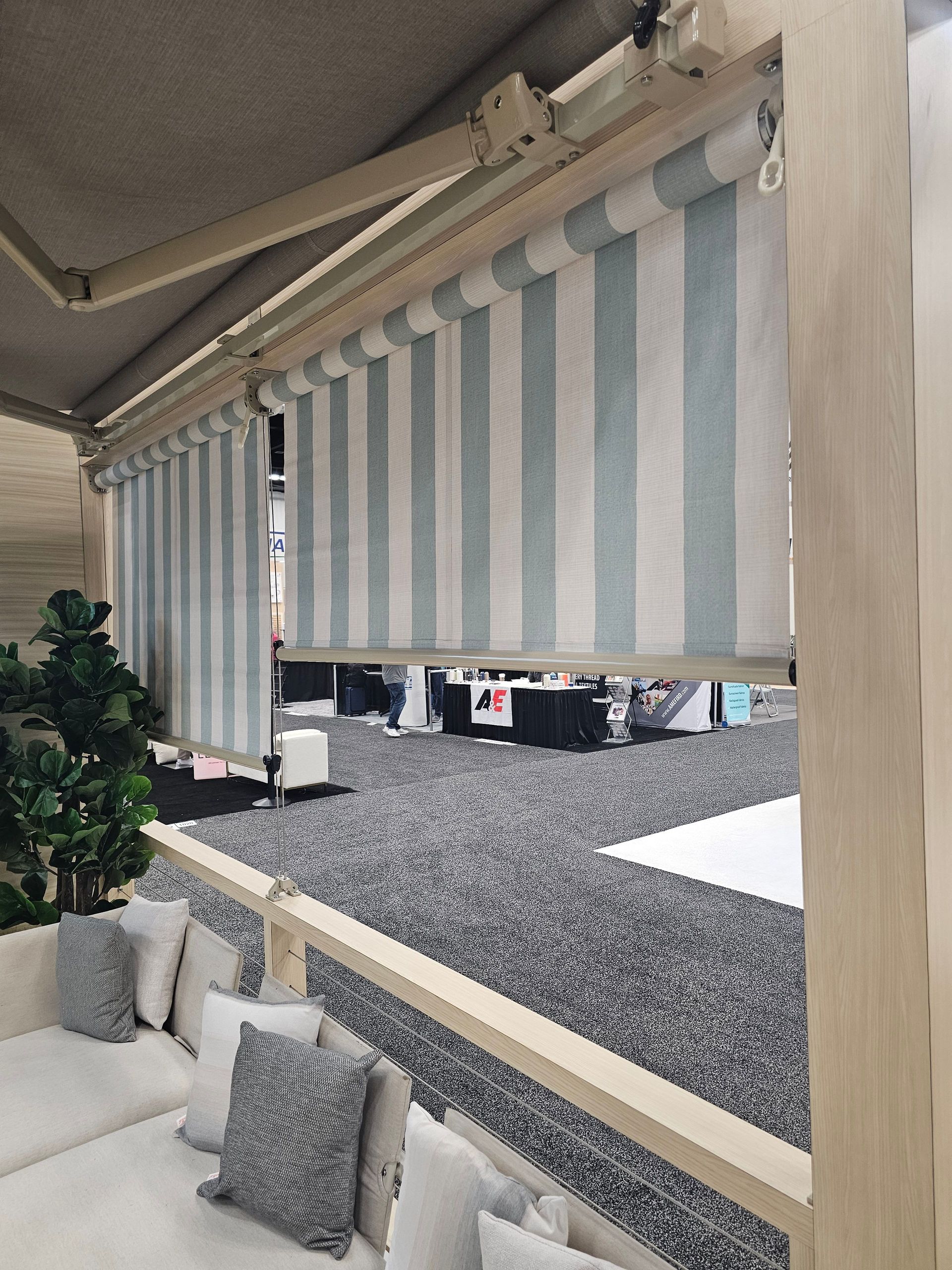 Striped awning above a patio with cushioned seating and a gravel-covered outdoor area.