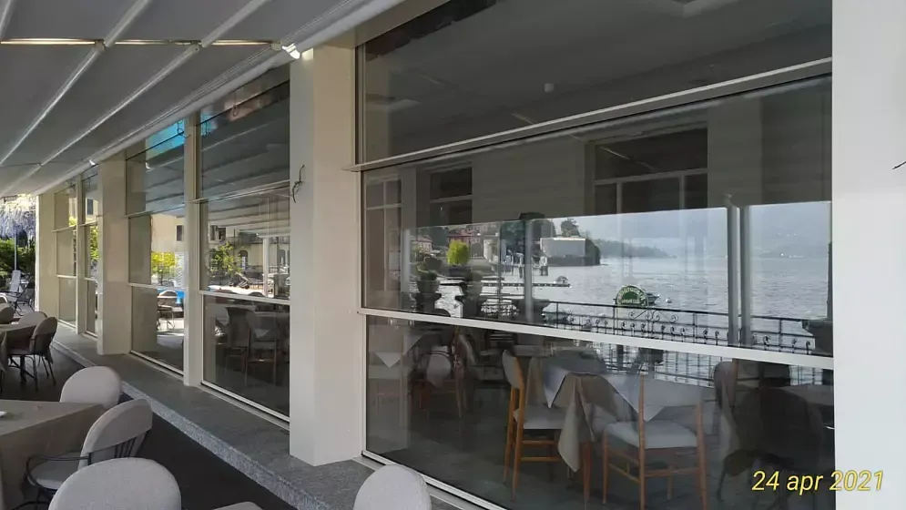 Outdoor café seating beside a glass storefront with tables, chairs, and a waterfront view