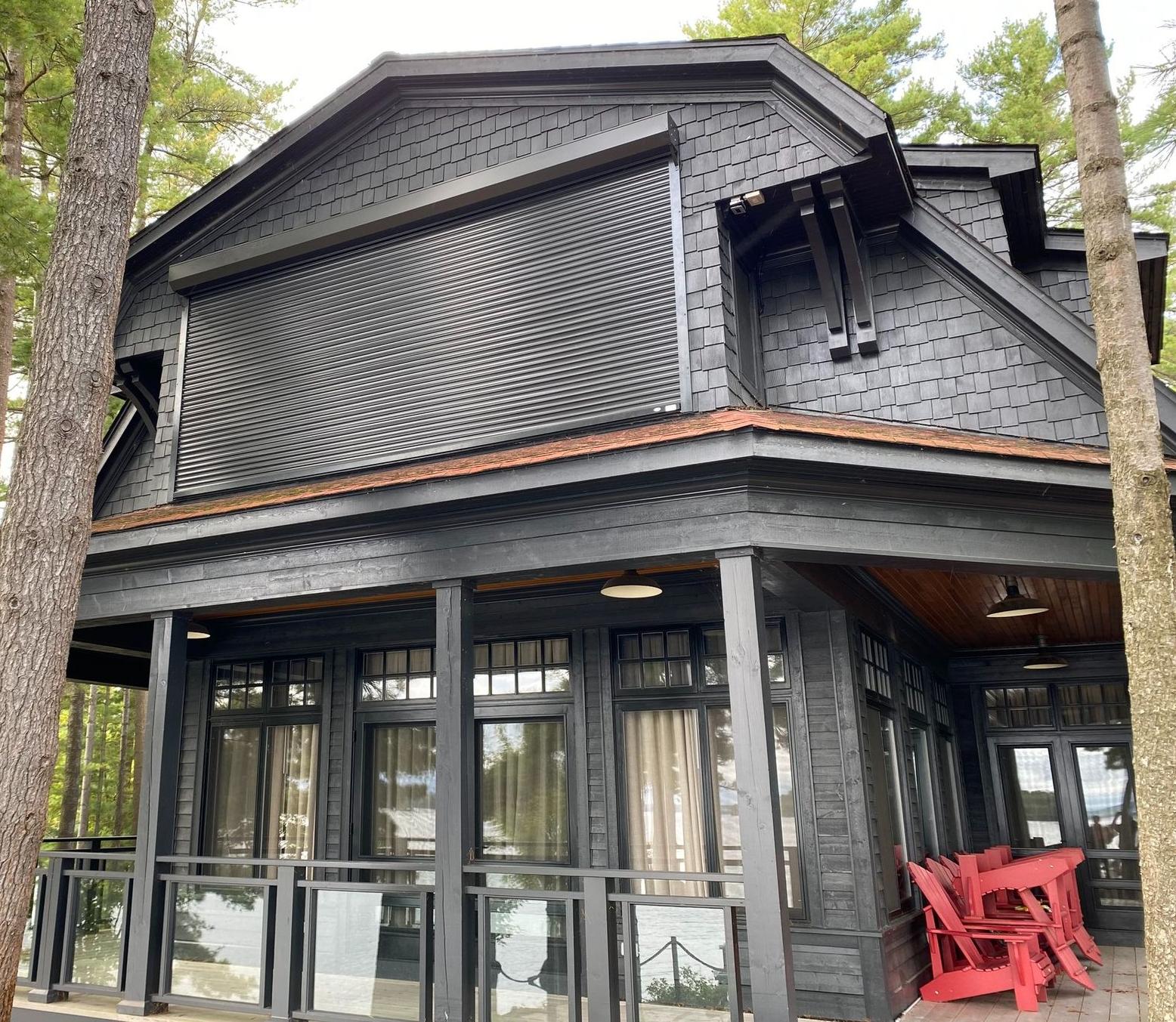 Black two-story building with patterned facade, large windows, and red chairs on the porch