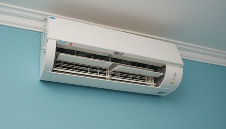 White air conditioning unit mounted on a light blue wall.