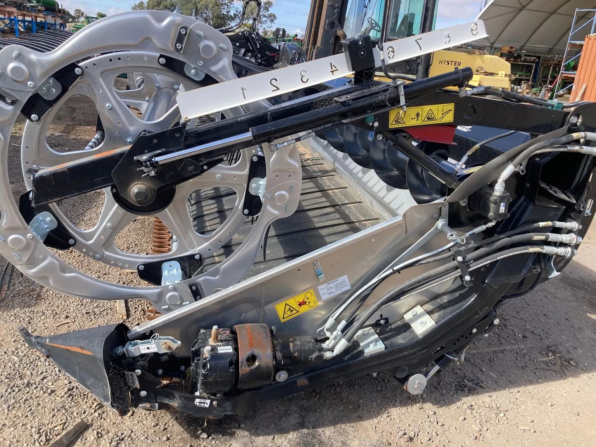 Damaged silver and black motorcycle parts scattered on pavement near a vehicle lift