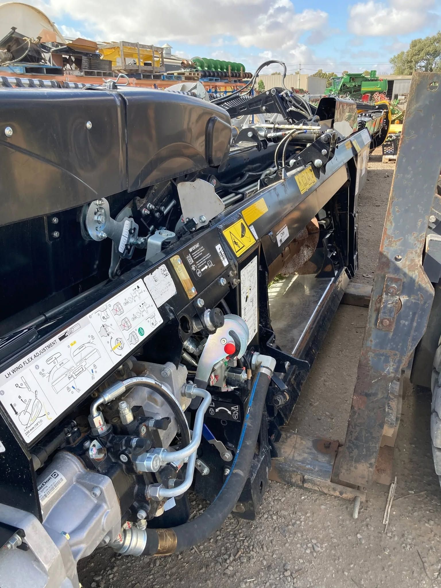 Damaged black machinery with exposed hoses and metal parts beside a curb on a road