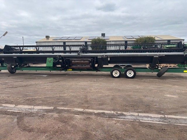 Long flatbed trailer carrying black metal equipment in an outdoor lot