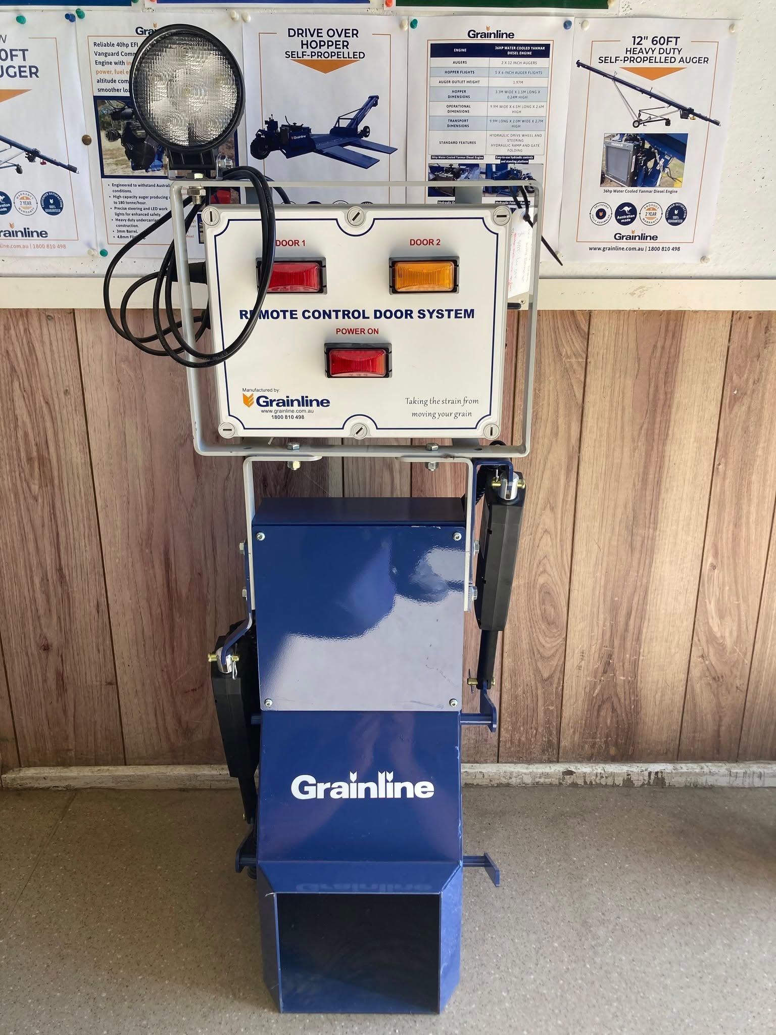 Blue Grainline machine with control panel and wiring, standing in a workshop against a wood wall.