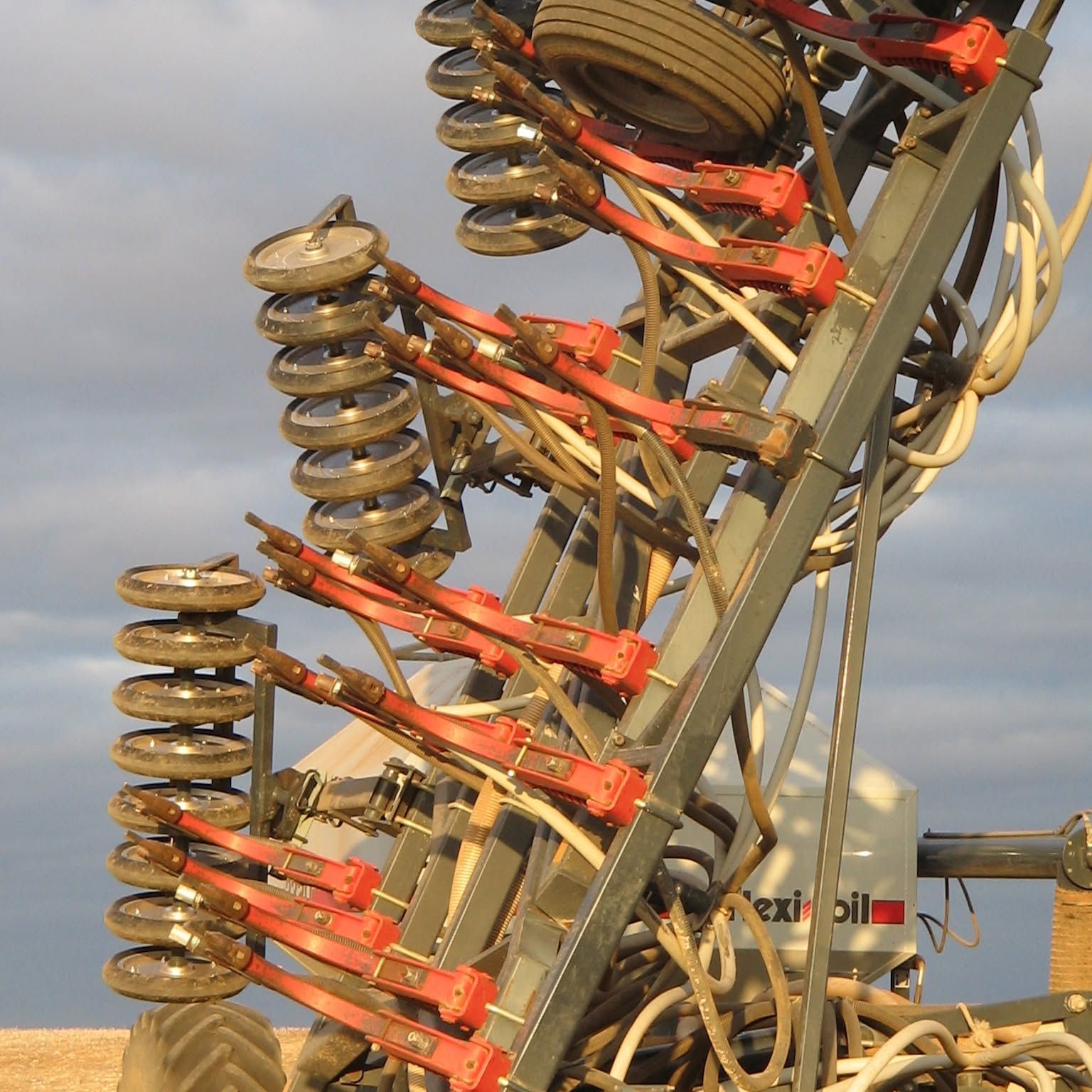 Close-up of stacked disc insulators and red brackets on industrial electrical equipment against the sky