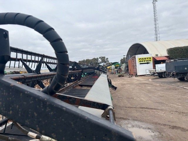 Damaged steel bridge on a construction site with heavy equipment and debris under a cloudy sky