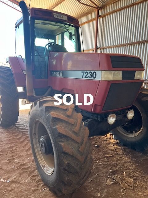 Maroon Case 7230 tractor in a shed with large tires and a SOLD sign on the front