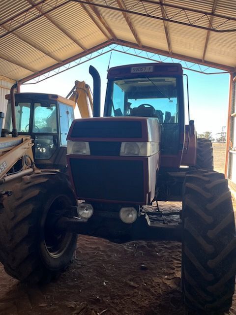 Two tractors parked inside a shed, viewed from the front