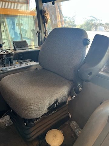 Gray bus driver seat inside a vehicle cabin, with dashboard and steering controls visible.