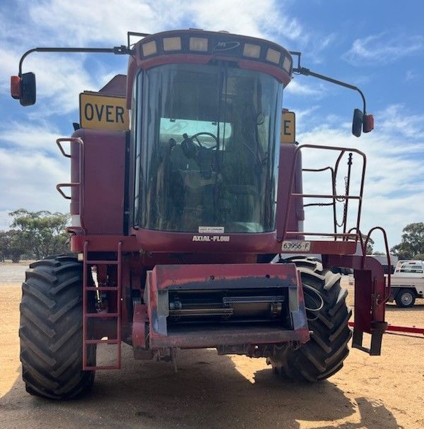 Front view of a red New Holland combine harvester on a dirt lot under a blue sky