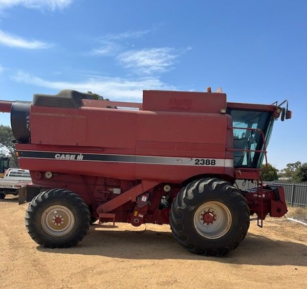 Red CASE IH combine harvester parked on a dirt lot under a blue sky