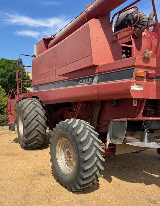 Red CASE combine harvester on a dirt path under a blue sky